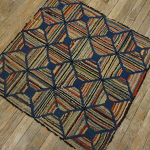 Textured multicolored rug featuring a navy blue geometric pattern sits on weathered wood plank flooring.