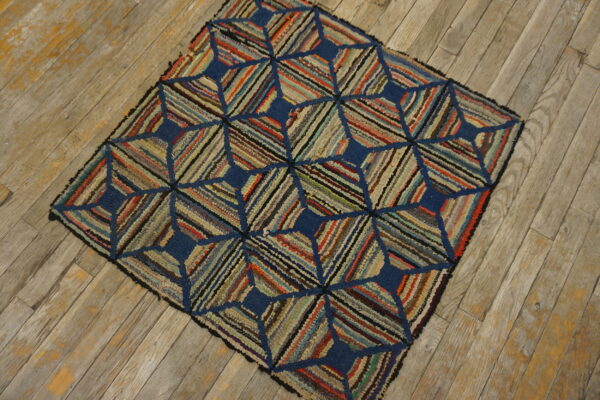 Textured multicolored rug featuring a navy blue geometric pattern sits on weathered wood plank flooring.