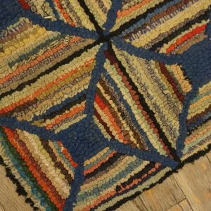 Multi-colored, high-texture rug with geometric blue and striped sections resting on distressed wood planks.
