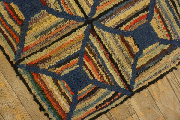 Multi-colored, high-texture rug with geometric blue and striped sections resting on distressed wood planks.