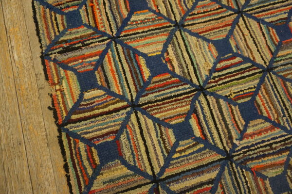 Multicolor rag rug with a blue diamond lattice pattern rests on aged wooden floorboards.