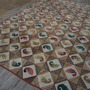 Cream and beige diamond rug with colorful botanical and striped patterns on worn wood flooring.