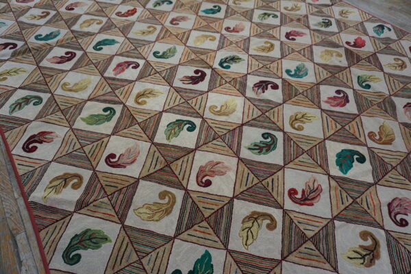 Cream hooked rug with a geometric grid pattern filled with multicolored leaves and textured stripes.