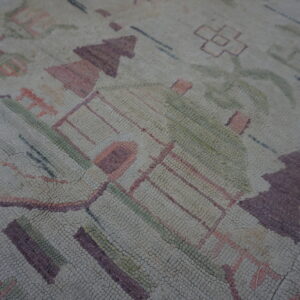 Detail of a rug with a knobby texture and abstract design in beige, purple, pink, and muted green.