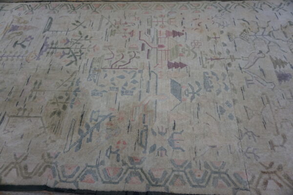 Cream rug with a sparse abstract pattern of faded pink, blue, and green geometric and folk motifs.