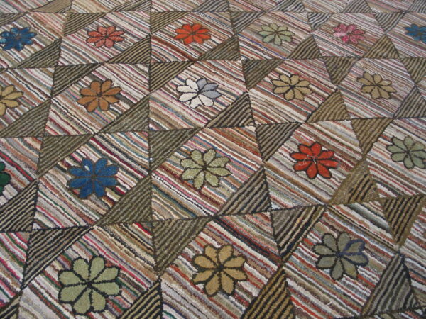 Textured rag rug featuring multicolored floral designs inside striped geometric diamond and triangle patchwork blocks.