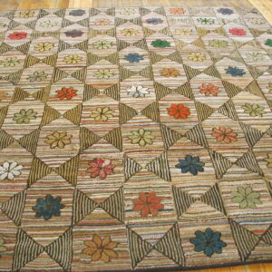 Geometric quilt-patterned rug featuring multicolored flowers set in striped squares on light wood flooring.