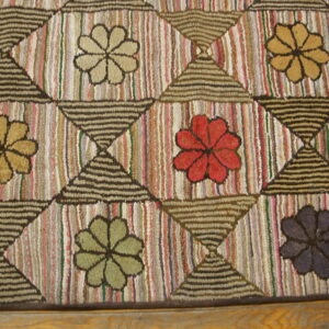 Textured rug featuring a geometric grid of hourglass shapes separating multi-colored floral medallions on striped backgrounds.
