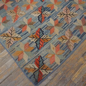 Multicolored leaf and geometric patterns cover a textured blue rug resting on rustic wood flooring.