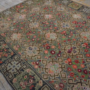 High-pile rug with geometric lattice and scattered multicolored floral designs resting on distressed hardwood floors.
