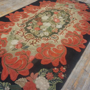 Textured rug with coral red floral scrolls on a dark border surrounding a cream and green center.