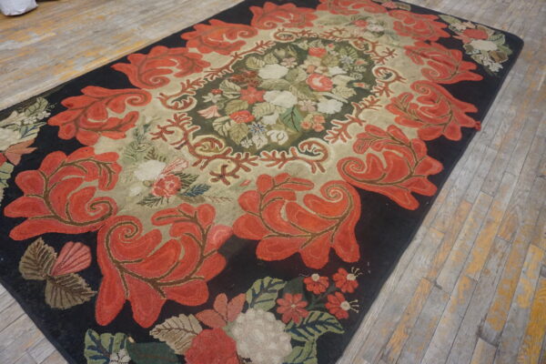 Textured rug with coral red floral scrolls on a dark border surrounding a cream and green center.