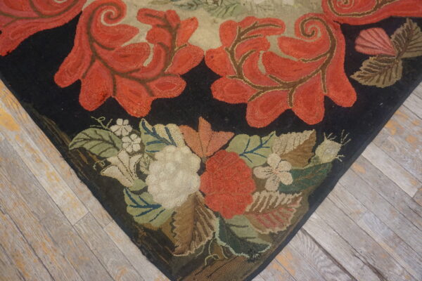 Black ground rug with looped red scrolled vines and detailed floral border on distressed wood plank floor.