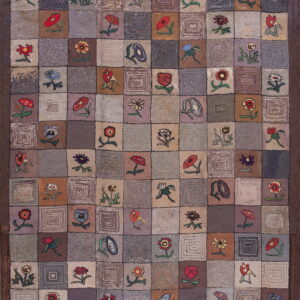 Muted checkerboard rug with a dark border, featuring alternating colorful floral motifs and abstract concentric square designs.