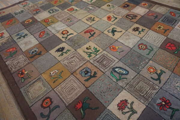 A textured rug featuring a colorful floral patchwork pattern on muted gray and brown squares.