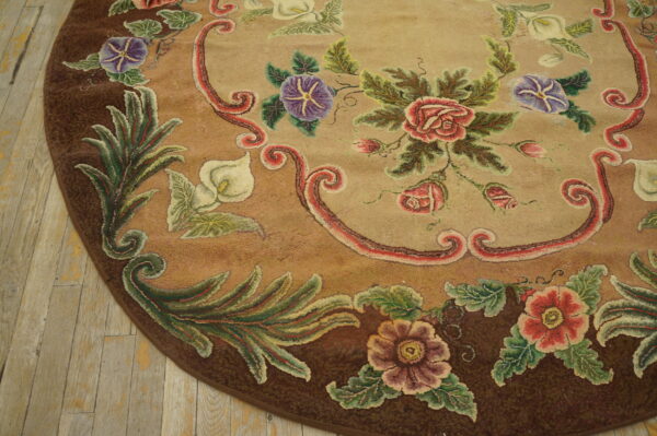 Tawny round rug featuring textured red, purple, and white botanical patterns, lying on distressed wood flooring.