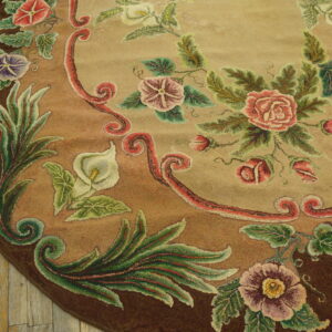 Textured round rug featuring colorful roses and foliage on tan and brown background over wood planks.