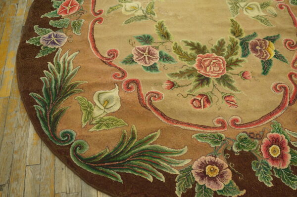 Textured round rug featuring colorful roses and foliage on tan and brown background over wood planks.