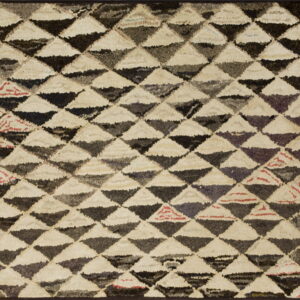High-pile rug featuring interlocking cream, dark gray, and black triangles in a dense geometric pattern.