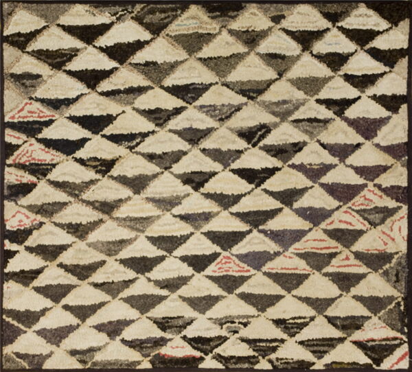 High-pile rug featuring interlocking cream, dark gray, and black triangles in a dense geometric pattern.