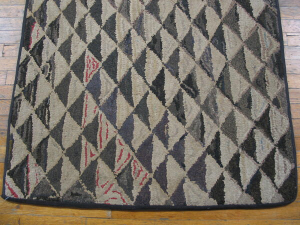 High-texture rug with geometric beige and dark brown triangles displayed on light wooden floorboards.