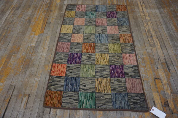 Multicolor patchwork rug with striped and speckled squares lying on distressed gray and yellow wood floor.