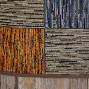 Highly textured, multicolor patchwork rug on rustic grey wood, featuring blocks of stripes and dashes.