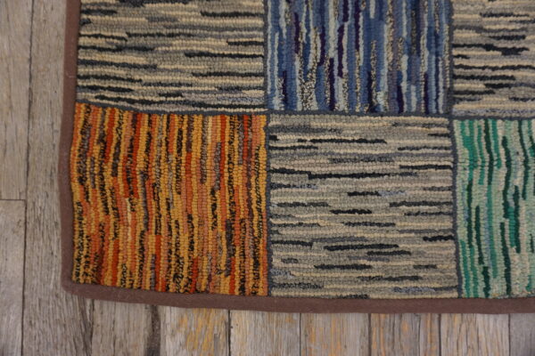 Highly textured, multicolor patchwork rug on rustic grey wood, featuring blocks of stripes and dashes.