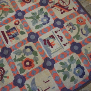Colorful textured rug featuring floral and novelty squares bordered by purple and coral lattice on wood plank flooring.