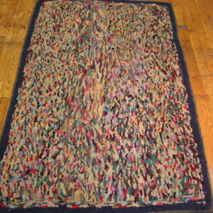 Shaggy, abstract rug in mixed bright colors with a navy blue border on wood planks.