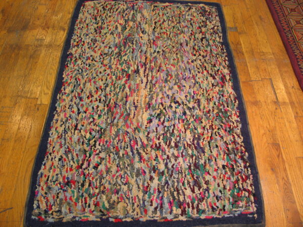 Shaggy, abstract rug in mixed bright colors with a navy blue border on wood planks.