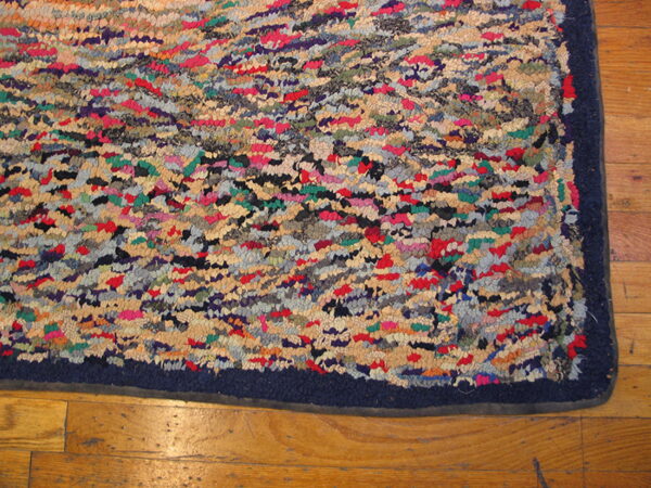 Multicolored shaggy rug featuring red, beige, green, and blue patches, with a navy border on wood planks.