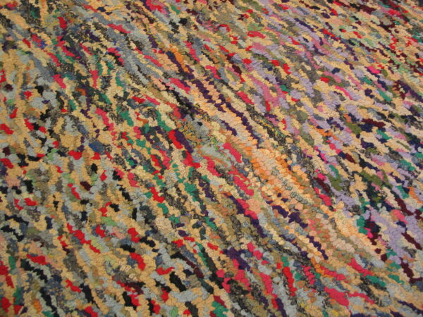 Multicolored rug with chunky, diagonal texture showing shades of red, blue, green, purple, and tan.