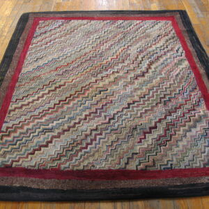 Multicolor zigzag rug with deep red and dark layered borders lying on light wood flooring.