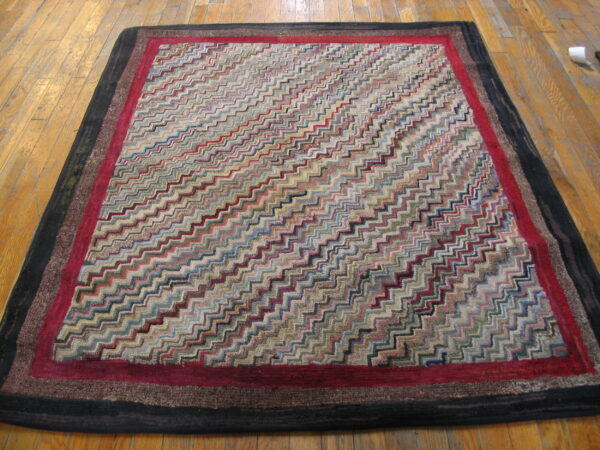 Multicolor zigzag rug with deep red and dark layered borders lying on light wood flooring.