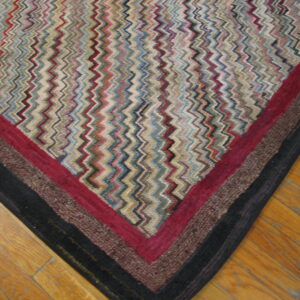 Multicolor, textured rug with a zigzag design and striped border resting on honey-toned wood floors.