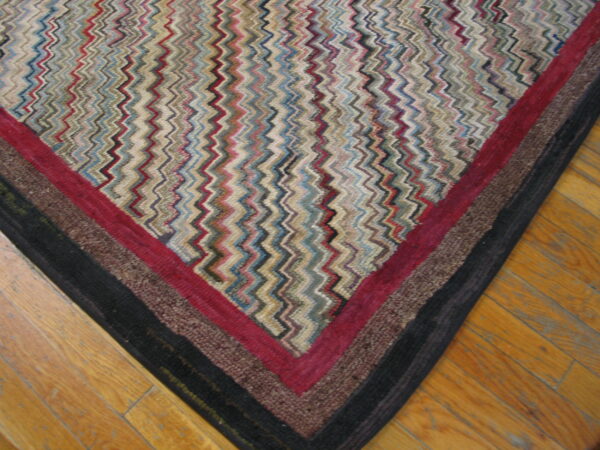 Multicolor, textured rug with a zigzag design and striped border resting on honey-toned wood floors.