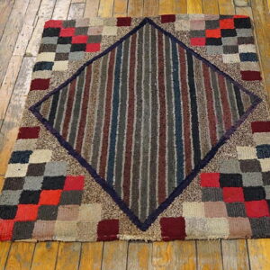 Multi-colored checkerboard rug featuring a striped red, gray, and blue central diamond on wood floorboards.