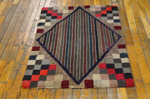 Multi-colored checkerboard rug featuring a striped red, gray, and blue central diamond on wood floorboards.