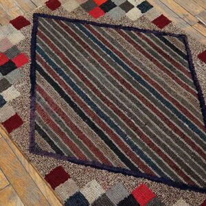 A textured rug featuring a central diamond of diagonal stripes bordered by multicolored checkered patches on a wood floor.