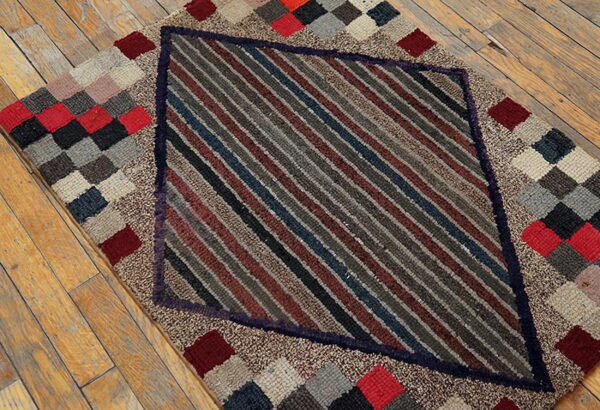 A textured rug featuring a central diamond of diagonal stripes bordered by multicolored checkered patches on a wood floor.