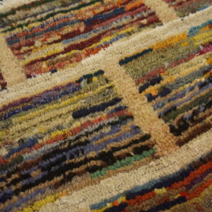 Shaggy rug texture showing thick cream lines separating dense blocks of multicolored fibers.