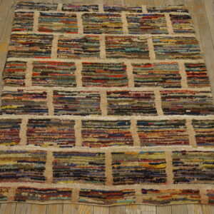 Shaggy multicolored rug with a geometric brick pattern defined by thick beige lines on wooden flooring.