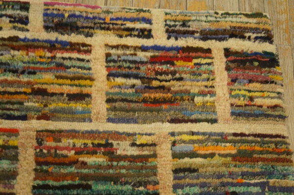 Textured high-pile rug with a cream grid pattern separating blocks of multicolored horizontal stripes on wood.