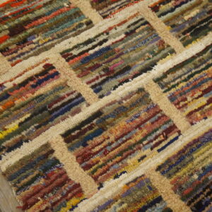 Shaggy, multicolored striped rug with a thick beige lattice pattern lying on gray wood plank flooring.