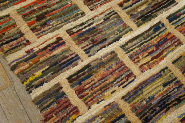 Shaggy, multicolored striped rug with a thick beige lattice pattern lying on gray wood plank flooring.