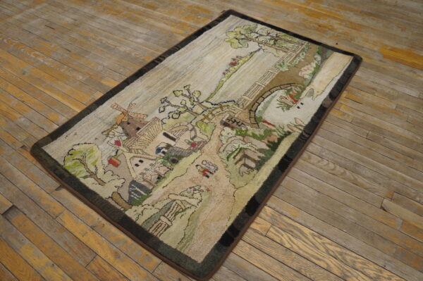Textured loop pile rug with a village scene, bridge, and windmill rests on distressed wood flooring.