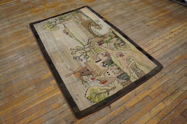 Pictorial rug depicting a village scene and trees with a dark border on rustic wooden floors.