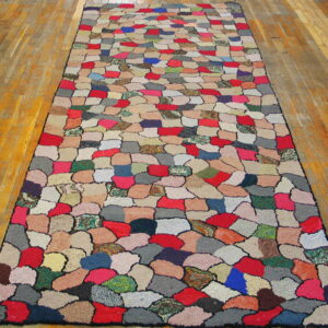 Multicolored patchwork runner rug featuring irregular, rounded shapes rests on a glossy wood plank floor.
