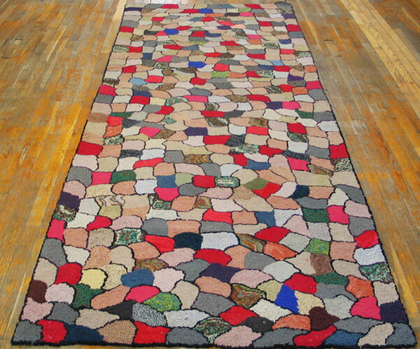 Multicolored patchwork runner rug featuring irregular, rounded shapes rests on a glossy wood plank floor.